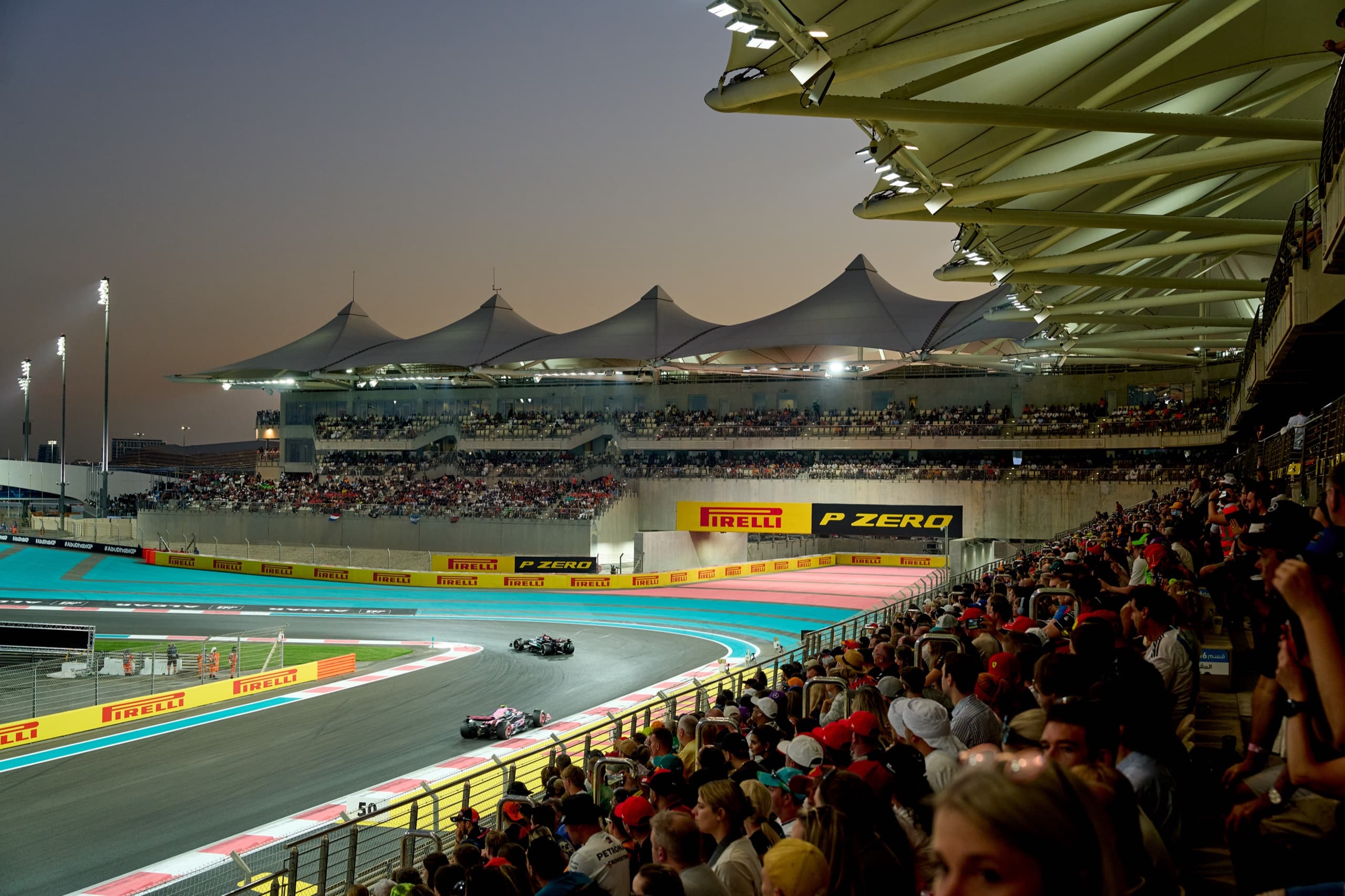 Cars through the floodlit turn at Yas Marina Circuit at dusk