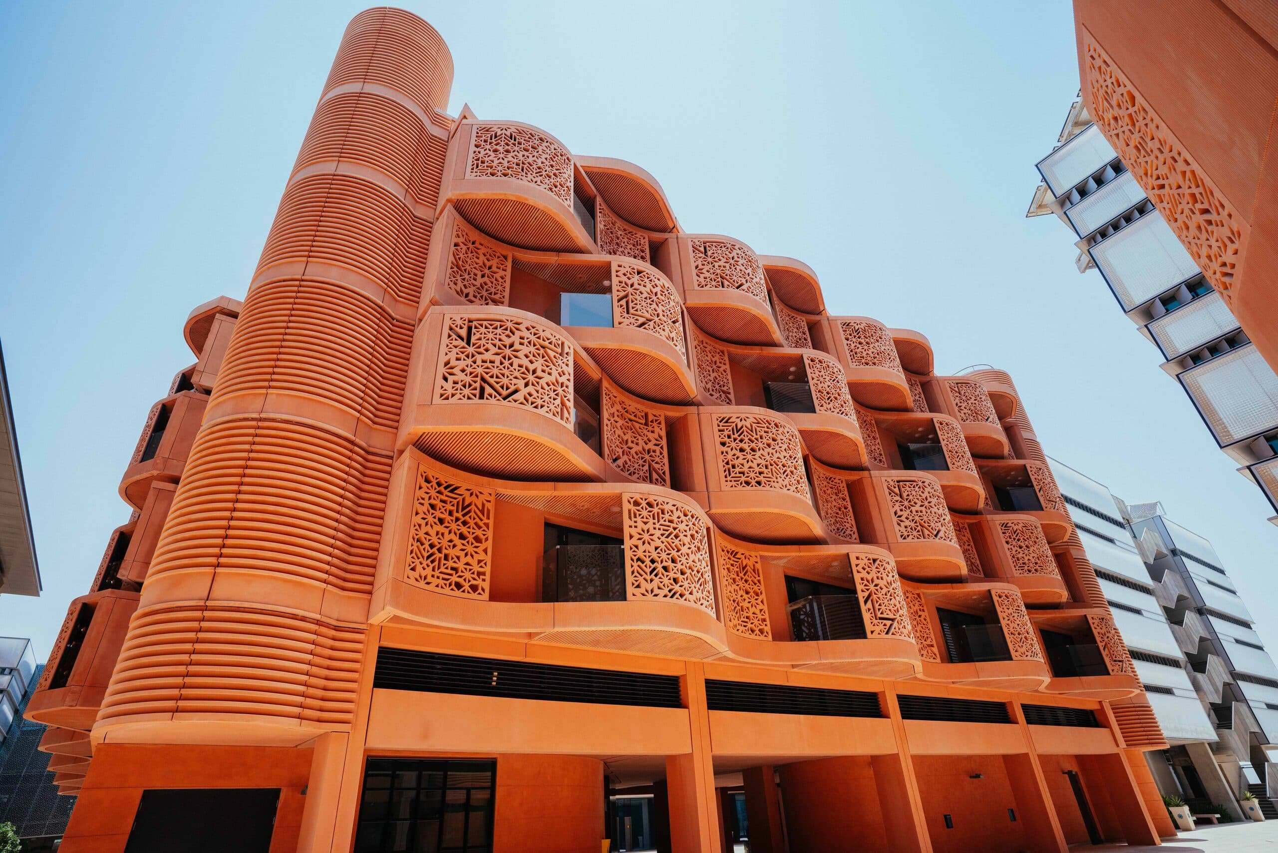 A Masdar City apartment building in terracotta, its balconies screened with carved panels